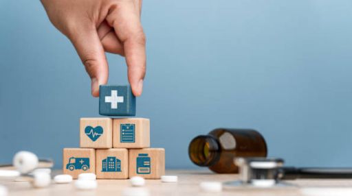 A hand placing 6 childrens blocks with medical insignia into a pyramid while medications are surrounding them.